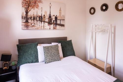 a bedroom with a bed with white sheets and green pillows at The Private Villa, Northampton Centre, 4 bedrooms, Sleeps 9 in Northampton