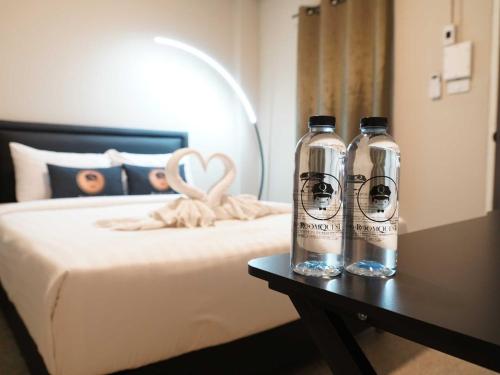 two bottles sitting on a table next to a bed at Dancenter Rq Bangkok Huai Khwang in Bangkok
