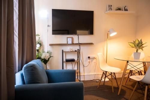 a living room with a blue couch and a table at The Private Villa, Northampton Centre, 4 bedrooms, Sleeps 9 in Northampton