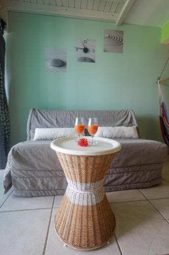 two glasses of wine on a table in front of a couch at KETYA Duplex Mabouya OU Studio Hamac in Le Gosier