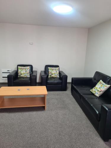 a living room with two black couches and a coffee table at Arran Motel in Te Anau