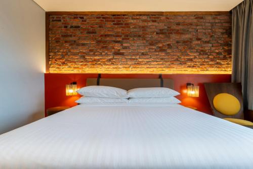 a bedroom with a white bed with a brick wall at Zaria Court Hotel Kigali in Kigali