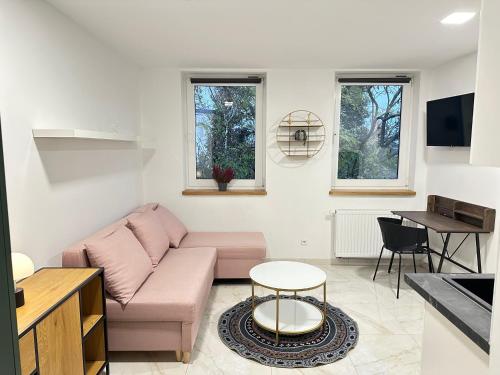 a living room with a pink couch and a table at MOVEEN! Wynajem apartamentów we Wrocławiu! 10 minut od centrum in Wrocław