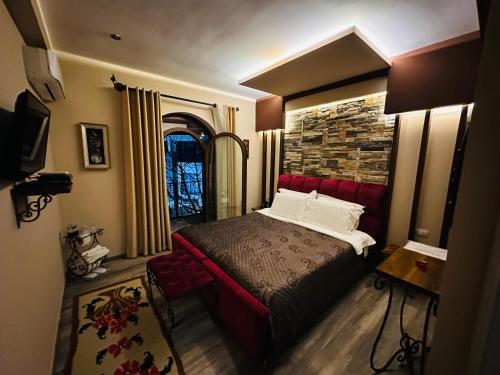 a bedroom with a red bed and a stone wall at Vila Eden Boutique Hotel in Korçë