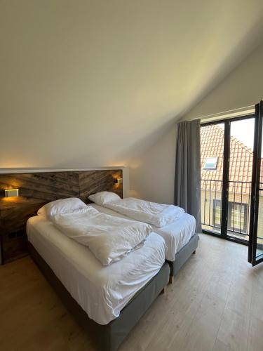 a bedroom with two beds and a large window at Tussen Dijken in Hollum