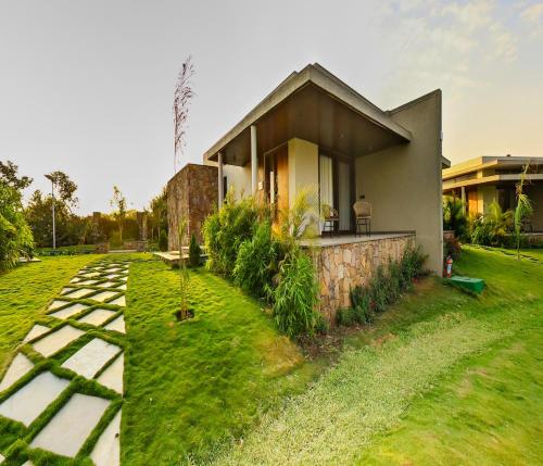 a house with a grassy yard next to a building at Araiya Gir,A Mavintara Resort in Chitrāwal
