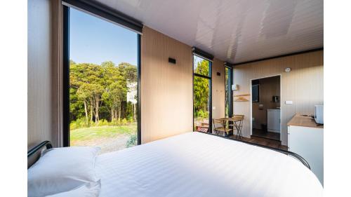 a bedroom with a bed and a large window at The Mini Mountain Hut 1 by Tiny Away in Egmont Village