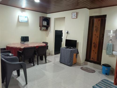 ein Zimmer mit Tisch und Stühlen und einem Fernseher in der Unterkunft Holiday cottage in Madikeri