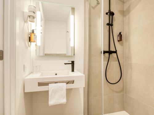 a white bathroom with a sink and a shower at B&B HOTEL Luxembourg Centre Cloche d'Or in Luxembourg