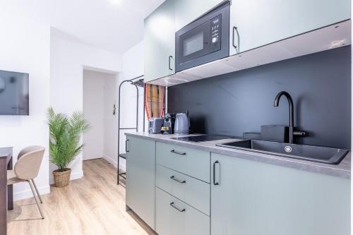 une cuisine avec des armoires blanches et un évier dans l'établissement Chic 4-Star Studio Only 10 Minutes from Le Marais, à Paris