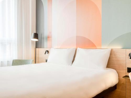 a bedroom with a white bed and a colorful wall at B&B HOTEL Luxembourg Centre Cloche d'Or in Luxembourg