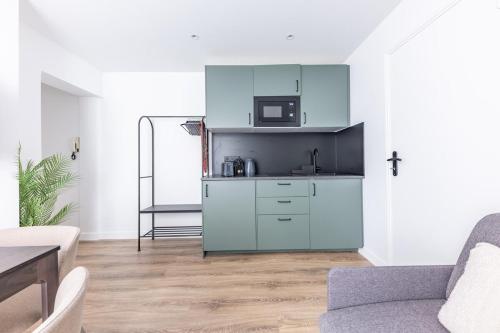 un salon avec une cuisine dotée de placards bleus dans l'établissement Chic 4-Star Studio Only 10 Minutes from Le Marais, à Paris