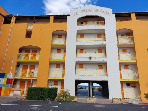 a yellow building with a sign that reads la palm beach at Appart avec loggia en front de mer et superbe vue in Le Barcarès