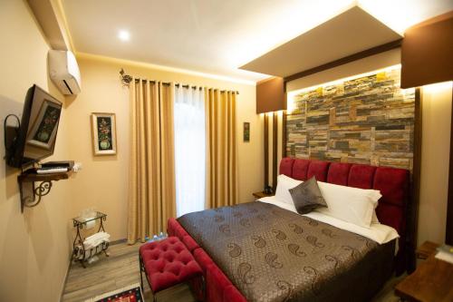 a bedroom with a red bed and a brick wall at Vila Eden Boutique Hotel in Korçë