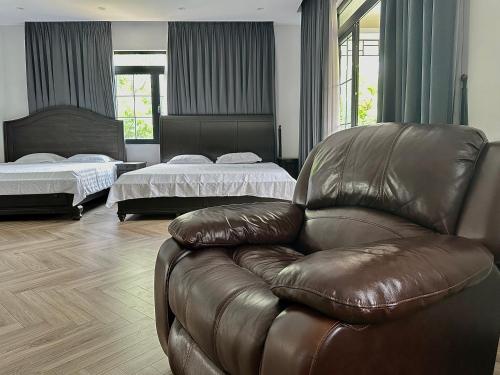 a living room with a leather couch and two beds at Tony Villa Homestay Ba Vì in Ba Vì