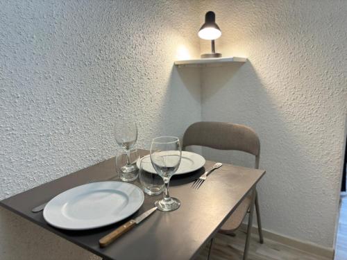 a table with two plates and wine glasses on it at Les Logis de Paray appartement n2 in Paray-le-Monial
