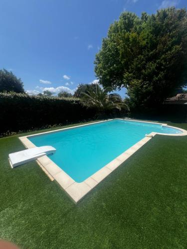 - une piscine avec un banc dans l'herbe dans l'établissement Villa La Hume proche port plage commodités Bassin d'Arcachon avec piscine chauffée, à Gujan-Mestras
