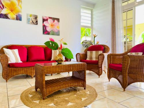 a living room with wicker chairs and a red couch at Villa Ahui Tautira with private lagoon access 