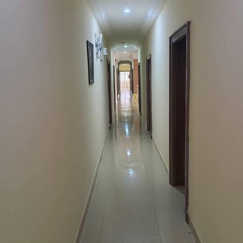 a hallway with white walls and a long hallway with doors at ANGELS COURT HOTEL and SUITES in Kuchbuni