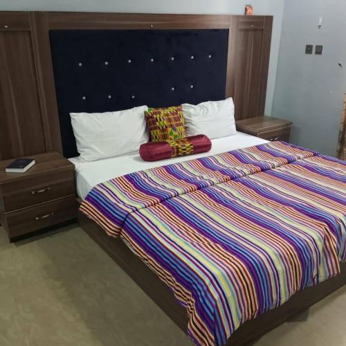 a bedroom with a large bed with a colorful striped blanket at ANGELS COURT HOTEL and SUITES in Kuchbuni