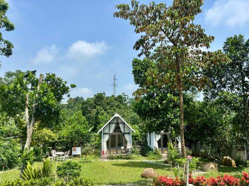 a small greenhouse in a garden with a tree at Tony Villa Homestay Ba Vì in Ba Vì