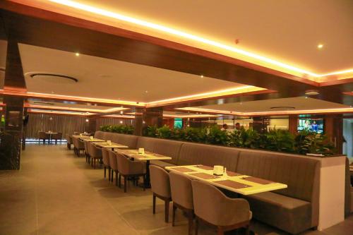a restaurant with tables and chairs and plants at Hotel Tulips Grand in Hyderabad