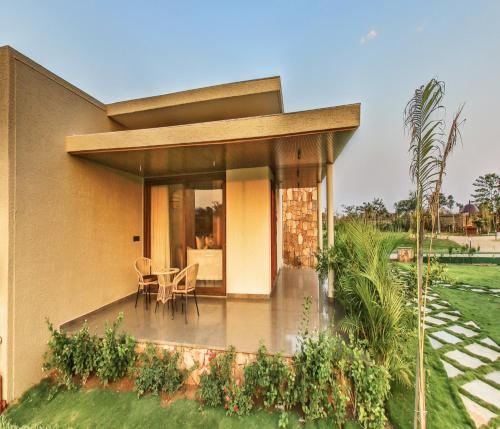 a house with a patio with a table and chairs at Araiya Gir,A Mavintara Resort in Chitrāwal