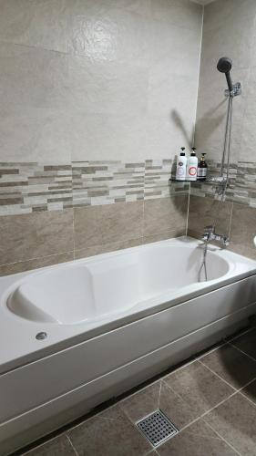 a white bath tub sitting in a bathroom at Galleria Hotel in Suwon