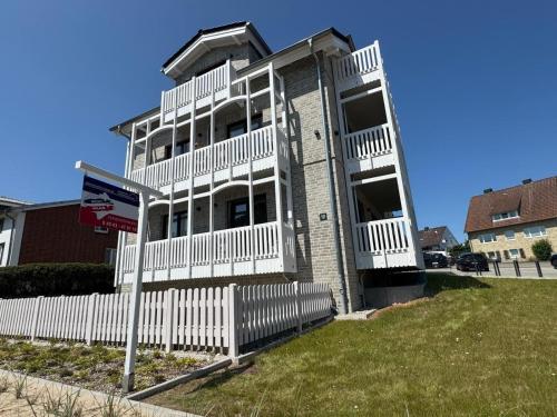 a building with a white fence in front of it at Salt & Sand Wohnung Sun in Haffkrug