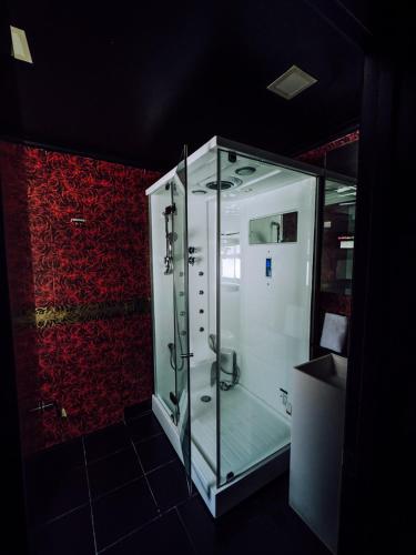 a glass shower in a bathroom with a red wall at Hotel Años 50 in Torremolinos