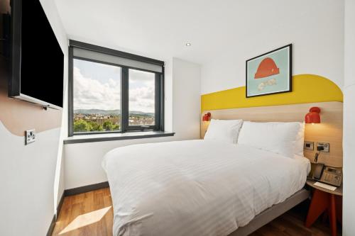 a bedroom with a large white bed and a window at Garner Hotel Edinburgh - Haymarket by IHG in Edinburgh