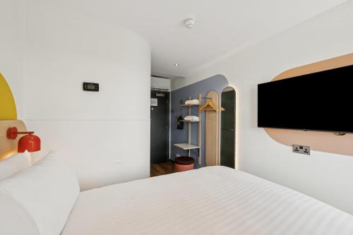 a bedroom with a white bed and a flat screen tv at Garner Hotel Edinburgh - Haymarket by IHG in Edinburgh