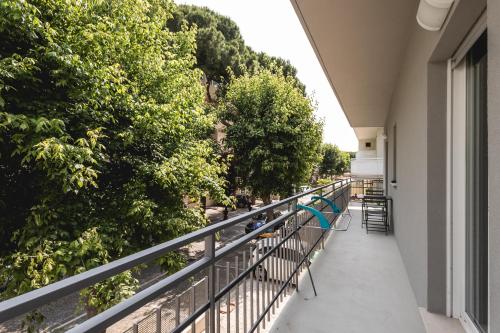 ein Balkon eines Gebäudes mit Bäumen und Stühlen in der Unterkunft Appartamento Sagittario in Misano Adriatico