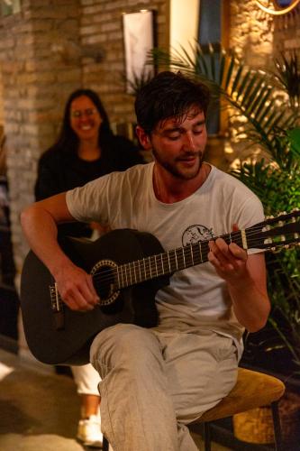 a man sitting on a chair playing a guitar at Black Swan Hostel Granada in Granada