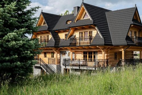 a large wooden house with a black roof at Bacówka Chalet in Zakopane