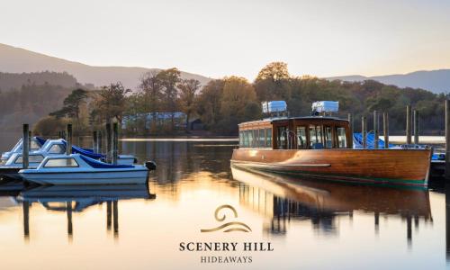 a boat is docked on a lake with other boats at Scenery Hill Hideaways The Coach House Charming Retreat with Jacuzzi and BBQ Hut Near the Lake District in Workington