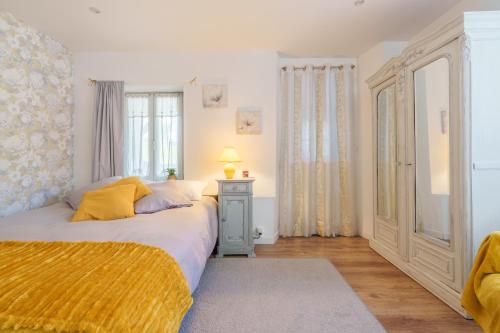 a bedroom with a bed with a yellow blanket on it at Aux Mirabelles Chez Florence Thierry in Bussang