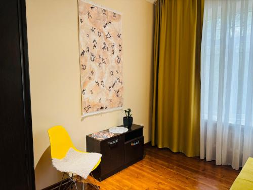 a room with a yellow chair and a table and a window at Уютный уголок рядом с ЦУМом и ГУМом 1 in Bishkek