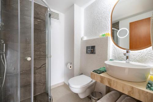 a bathroom with a toilet and a sink and a mirror at Petunya Beach Resort in Ortakent