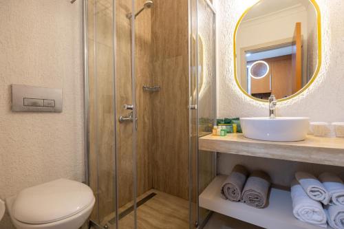 a bathroom with a toilet and a sink and a mirror at Petunya Beach Resort in Ortakent