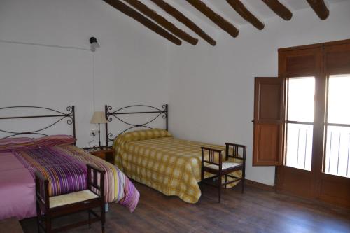 a bedroom with two beds and two chairs and a window at Cortijo de los Castellanos in Las Ventanas