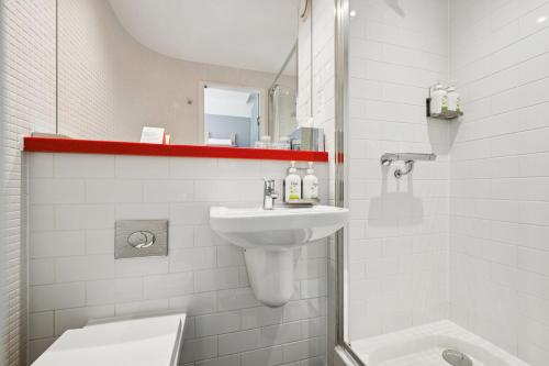 a white bathroom with a sink and a toilet at Garner Hotel Edinburgh - Haymarket by IHG in Edinburgh