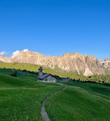 a church in a field with mountains in the background at Hotel Arnaria in Ortisei