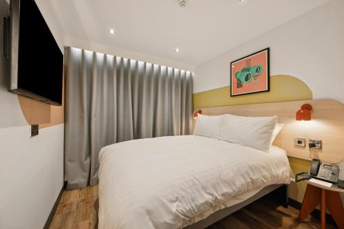 a bedroom with a white bed and a television at Garner Hotel Edinburgh - Haymarket by IHG in Edinburgh