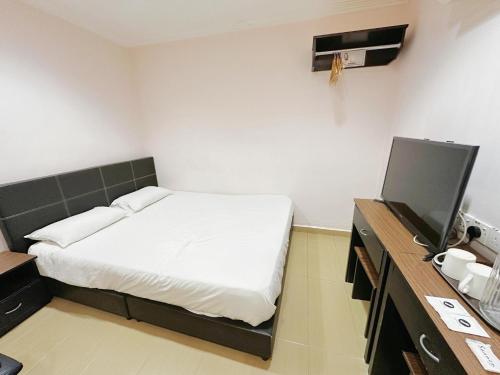 a bedroom with a bed and a desk with a tv at Hotel O Tasik Utama in Malacca