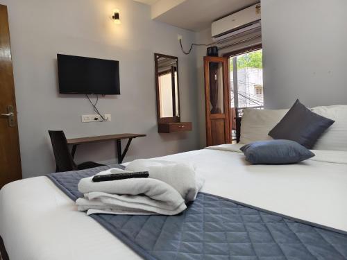 a bedroom with two beds and a television on the wall at Lax Residency, White Town, Pondicherry in Puducherry