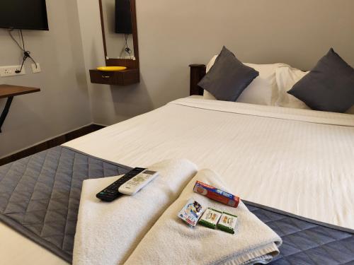 a bed with two remote controls and towels on it at Lax Residency, White Town, Pondicherry in Puducherry