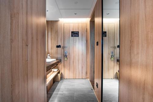ein Badezimmer mit Holzwänden, einem Waschbecken und einem Spiegel in der Unterkunft Atour Hotel Hangzhou Xiaoshan Peoples Square in Hangzhou