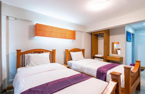 a bedroom with two beds and a mirror at GO INN Khaosan Bangkok - โกอินน์ ถนนข้าวสาร in Bang Bua Thong Railway Station