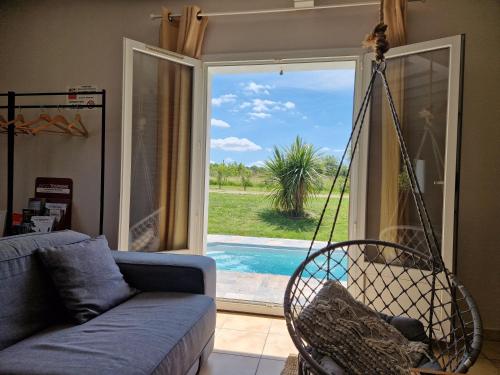une balançoire dans un salon avec vue sur une piscine dans l'établissement Le Grand Cottage Nature Piscine Chauffée Privée du Tarn entre Toulouse et Albi & Les Cottages du Tarn, à Peyrole